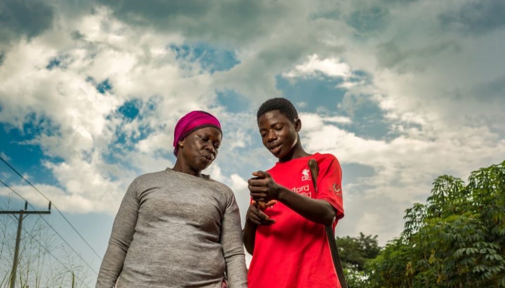 A woman and a boy look at a phone that provides them with weather forecast data from Ignitia