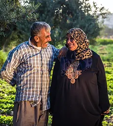 Smiling man and woman standing together in a green field. Click to learn more about Agriculture.
