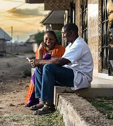 Man and woman sitting on steps, smiling and talking. Click to learn more about Financial Empowerment.